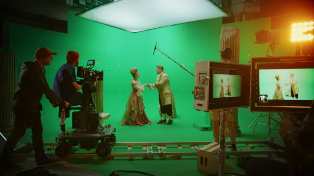 On Big Film Studio Professional Crew Shooting Period Costume Drama Movie. On Set: Director Controls Cameraman Shooting Green Screen Scene with Two Actors Talented Wearing Renaissance Clothes Talking