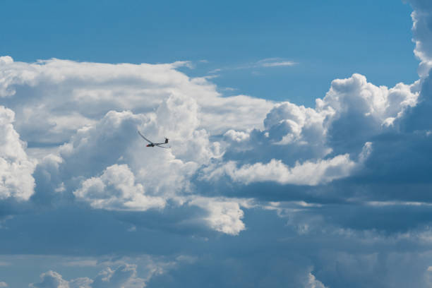 A small glider in front of giant clouds after the storm. The clouds break open and blue sky appears.