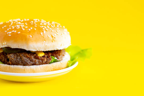 istock Fresh tasty hamburger on bright yellow background copy space banner 1250939393