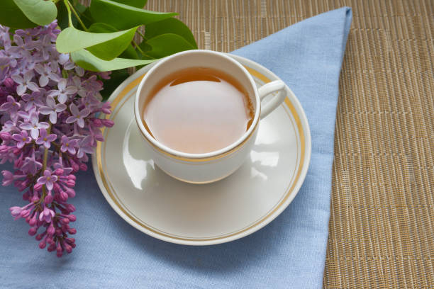istock Cup with tea and a branch of lilac on a blue background 1250940090