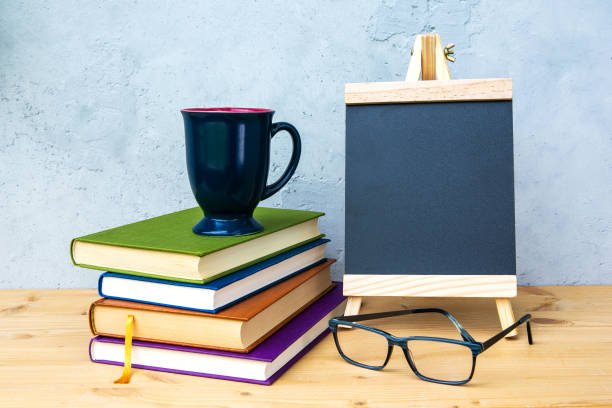 istock small chalkboard on wooden table with books, cup and eyeglasses with grey background 1250940853