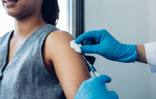 istock Doctor Holding Syringe By Patient In Background 1250942203