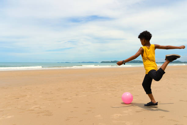 Young boy plays ball on the beach with happy mood. summer and vacation concept. Full body composition.