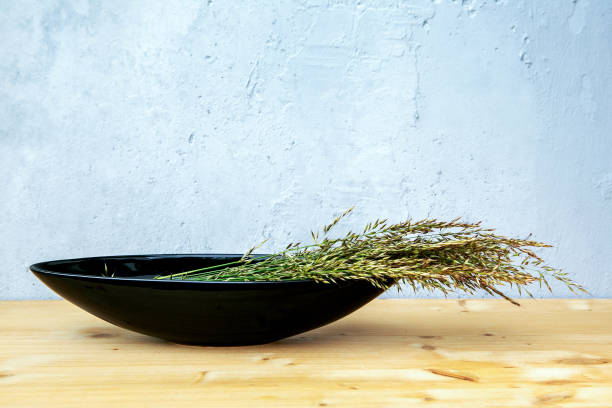 istock black bowl with blades of grass on table with grey background 1250943251
