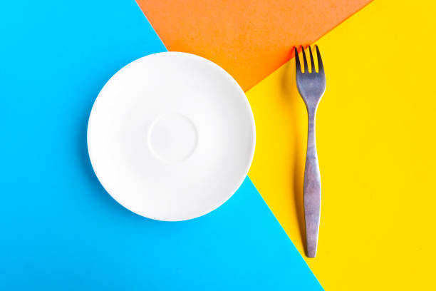 istock White mockup plate and fork on color geometric background. Copy space for the text. Minimal concept 1250944228