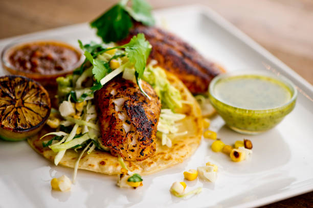 istock Fish tacos served on homemade corn tortilla with shredded cabbage, grilled corn, queso Fresca, jalapeños served with cilantro, guacamole and spicy salsa verde. Classic Mexican or Tex-Mex street food favorite. 1250949005