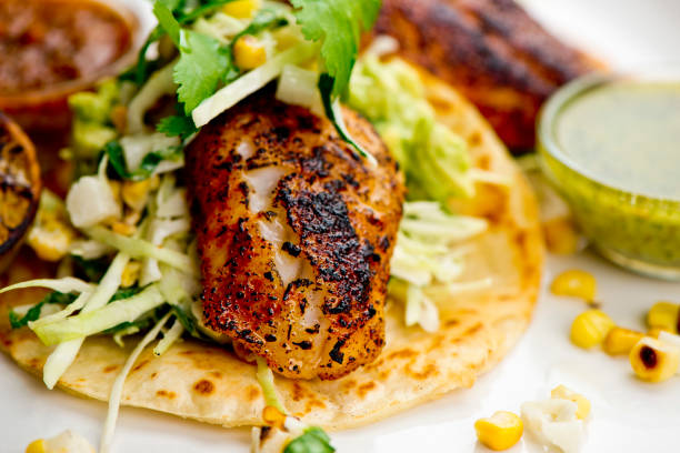 istock Fish tacos served on homemade corn tortilla with shredded cabbage, grilled corn, queso Fresca, jalapeños served with cilantro, guacamole and spicy salsa verde. Classic Mexican or Tex-Mex street food favorite. 1250949021