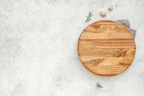 Empty wooden round board Empty wooden round board on white stone kitchen table, top view, flat lay. Wooden pizza platter, copy space. cooking with garlic stock pictures, royalty-free photos & images