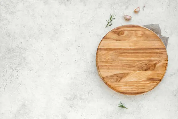 Empty wooden round board on white stone kitchen table, top view, flat lay. Wooden pizza platter, copy space.