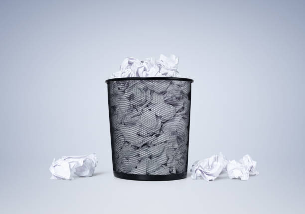 istock Office black waste bin full of white crumpled paper on blue background. File contains a path to isolation. 1250950722