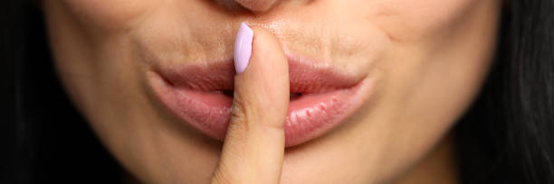 istock Beautiful woman put her finger to closed red lips 1250955974