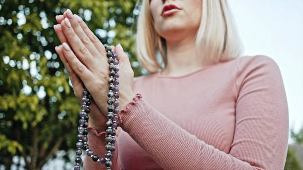 istock Woman's hands with mala beads or prayer beads together symbolizing prayer and gratitude. Mudra. Yoga concept. Concentrated girl standing with hands in namaste and meditating or praying. 1250959666