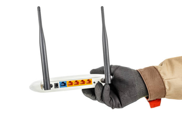 istock Wireless wi-fi router with colored connection ports on back panel in man hand in black protective glove and brown uniform isolated on white background 1250962023
