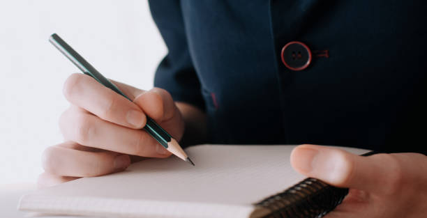 istock Female hands with pencil writing on notebook. Hand with pen writing on notebook. 1250962062