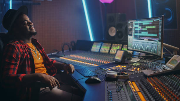 istock Energetic Audio Engineer / Producer Chill in Music Recording Studio, Mixing Tracks on Control Desk and Software to Create Distinctive Sound of Hit Song. Portrait of Black Artist Musician. 1250963246