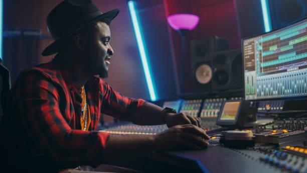 istock Stylish Male Audio Engineer Working in Music Recording Studio, Uses Mixing Board, Software to Create Modern Hit Song. Creative Artist Musician Working on Workdesk Control Surface to Produce New Song 1250963281