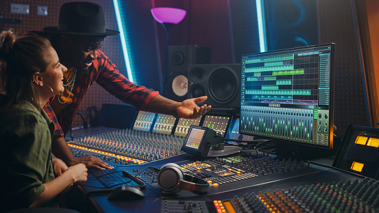 Productor e ingeniero de audio profesional trabajando juntos en Music Recording Studio en un nuevo álbum, Talk, Use Control Desk Equalizer, Mixing Board y software para crear Hit Song. Artista y músico photo