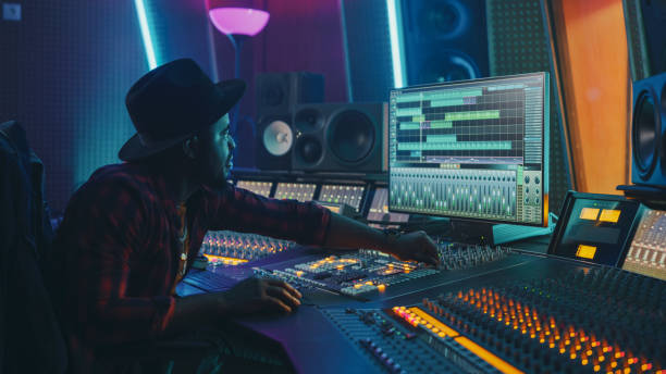 istock Stylish Audio Engineer / Producer Working in Music Record Studio. Computer Screen Showing User Interface of Digital Audio Workstation Software with Track Song Playing. Uses Control Desk to Create Song 1250963420