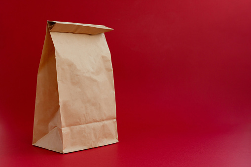 brown paper craft bag for shopping on a red background