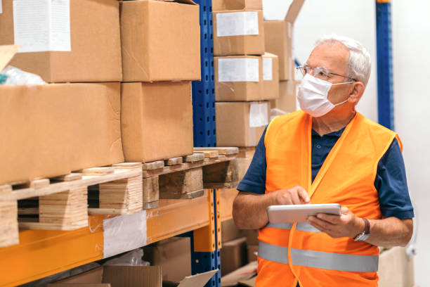istock Senior manager wearing protective face mask, using digital tablet and working in a warehouse 1250966275