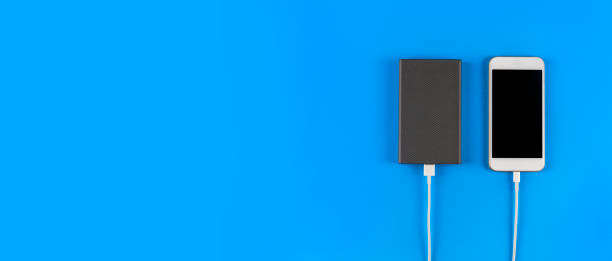 istock Top view smartphone charging with power bank on blue background with copy space. Smartphone charging with power bank by white USB cable. 1250966346