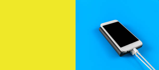 istock Top view smartphone charging with power bank on blue and empty yellow background with copy space. Smartphone charging with power bank by white USB cable. 1250966455