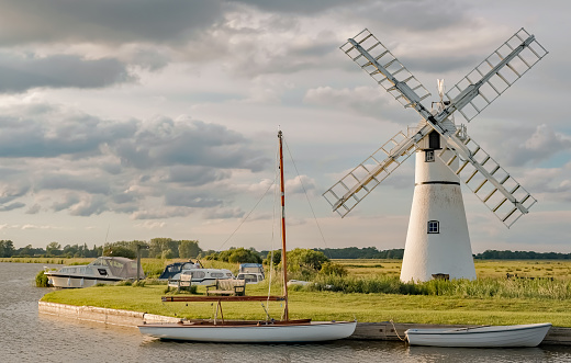 Thurne Mill on the waterside of Thurne River mouth in the Norfolk Broads National park on a cloudy summers evening