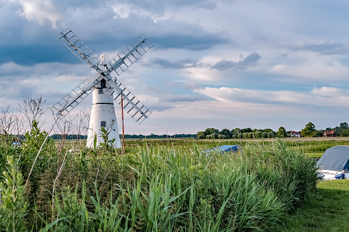 The infamous Thurne mill on the riverbank at Thurne Mouth in the Norfolk Broads National Park on a cloudy summer evening