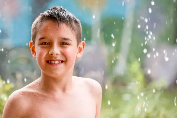 boy in the garden with a colorful background
playing in the rain, child getting wet from the raindrops, happy kid dancing, rain drops