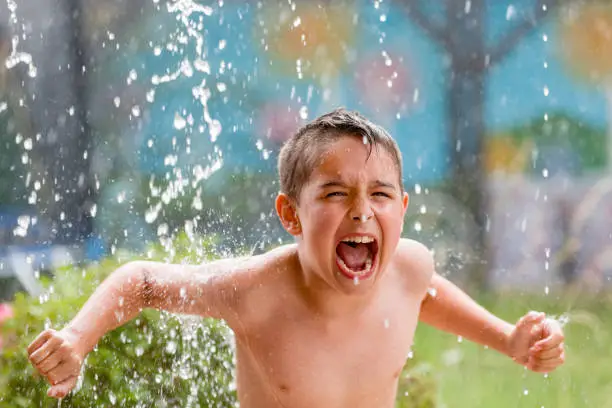 boy in the garden with a colorful background
playing in the rain, child getting wet from the raindrops, happy kid dancing, rain drops