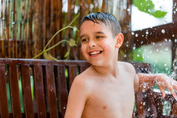 boy in the garden with a colorful background
playing in the rain, child getting wet from the raindrops, happy kid dancing, rain drops