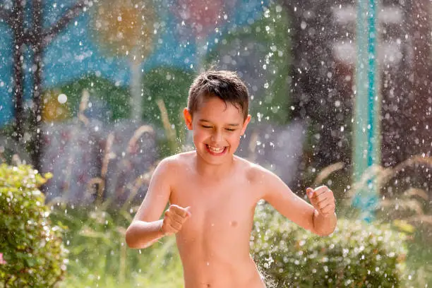 boy in the garden with a colorful background
playing in the rain, child getting wet from the raindrops, happy kid dancing, rain drops