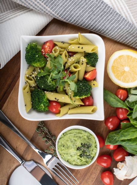 Gluten-free fresh cooked penne pasta from green peas isolated on wooden board. basil