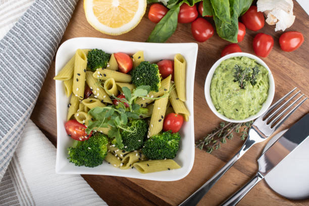 Gluten-free fresh cooked penne pasta from green peas isolated on wooden board. basil