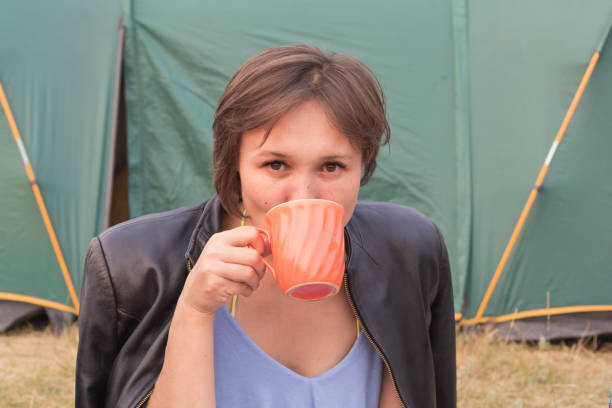 istock Pretty young woman idrinking tea from a large mug and looking at the camera 1250975297