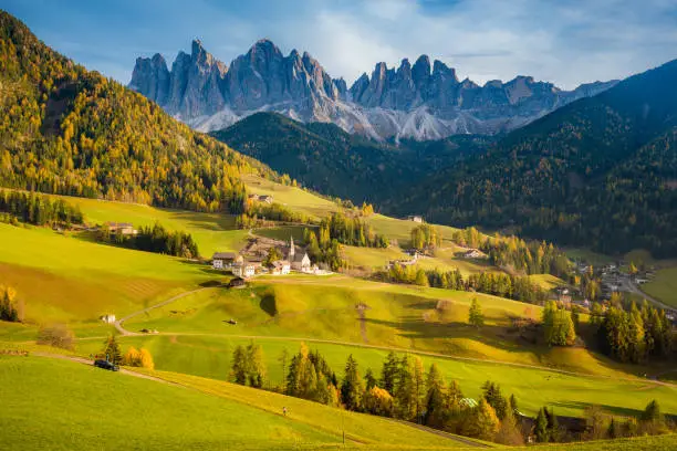 Beautiful view of idyllic mountain scenery in the Dolomites with famous Santa Maddelana mountain village in beautiful golden evening light at sunset in fall, Val di Funes, South Tyrol, northern Italy.