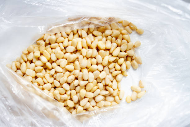 istock Peeled pine nuts in a plastic bag on a white background 1250980856