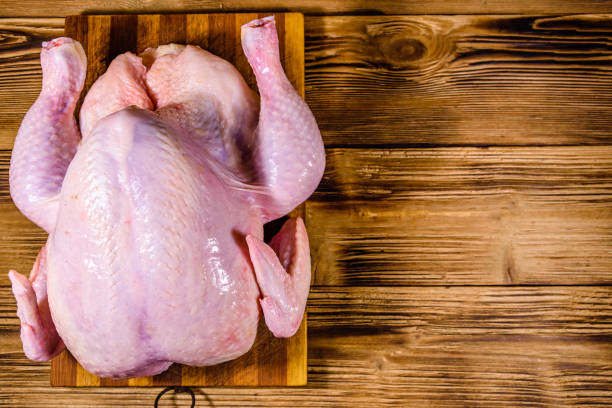 istock Wooden cutting board with the whole uncooked chicken. Top view 1250980967