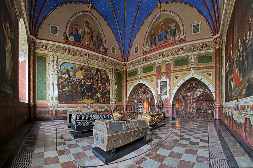 Roskilde, Denmark - December 14, 2015: Panorama of interior of Christian IV's chapel in Roskilde Cathedral with the sarcophagi of king Christian IV of Denmark, his wife Anne Catherine of Brandenburg, his sons king Frederick III of Denmark with wife Sophie Amalie of Brunswick-Luneburg, and Christian, Prince-Elect of Denmark. The chapel was built in 1614-1641. The interior of the chapel was completed in 1870 including the frescoes by Heinrich Eddelien, and paintings with decor by Wilhelm Marstrand and Heinrich Hansen. The statue of Christian IV was created by Bertel Thorvaldsen.