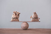 Gain and loss bags on a basic balance scale on a blackboard. Capital investment gain and loss, financial concept, depicts balancing between profit and loss while managing assets e.g bonds, stocks, derivatives, ETFs