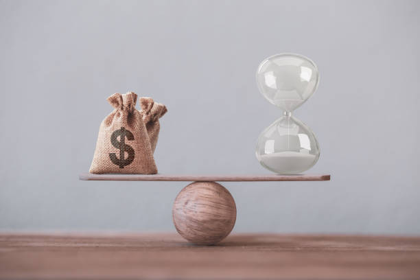 istock Write sand clock or hourglass symbol and dollar bagson a balance scale in equal position. Financial concept : Time value of money, asset growth over time, depicts investment in long-term equity for more money growth 1250984671