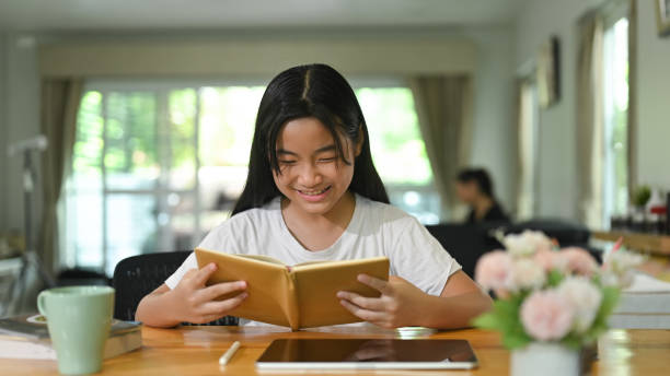 una niña leyó un libro en un escritorio de madera. estudiar en el concepto de casa. - open book teaching table fotografías e imágenes de stock