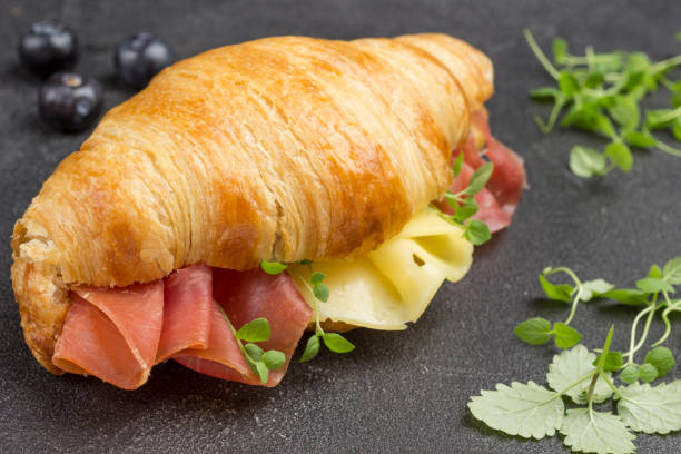 istock Croissant with jamon and cheese. Greens on table. 1250986992