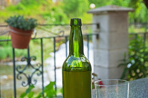 Glass vase and bottle of Cider (fermented apple juice).  On outdoor bar terrace and unfocused background - Glass glass and bottle of Cider (fermented apple juice).  On outdoor bar terrace and unfocused background