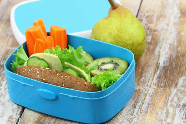 Photo of Healthy packed lunch with brown cheese sandwich, crunchy carrots, kiwi fruit and pear