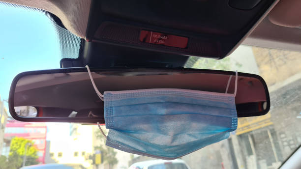 istock Surgical mask hanging on a rear view window in the car 1250989973