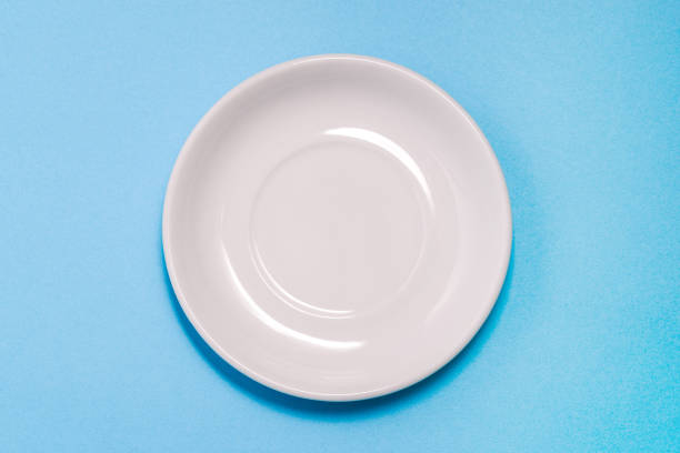istock An empty white plate on a blue background. Clean dishes for Breakfast, dinner or lunch. Kitchen items. A top view of a flat layout. 1250992828