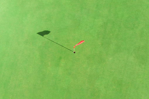top view of golf pole on the green in a golf course with blank copyspace