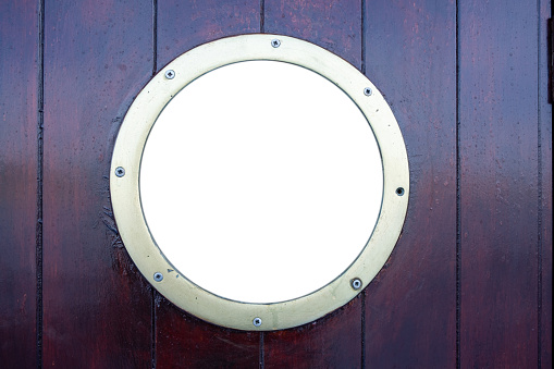 Ship porthole on brown wooden wall background. Round boat scuttle, empty blank white glass, mockup, template, copy space