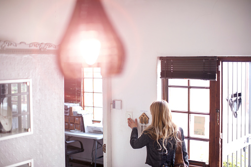 A Small business owner turning on the lights in her jewelry store.